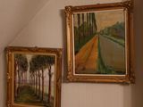 two paintings on the wall above a bed in a room