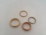 four gold wedding rings on a white surface