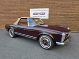an image of a maroon convertible car parked in front of a building