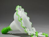 a white and green vase with green beads on it