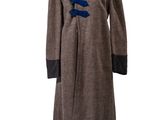 Ce manteau est en laine et comporte un ruban bleu au niveau du col.