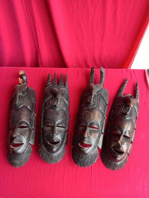 four wooden masks are lined up on a red cloth