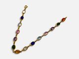 un bracelet en or avec des pierres multicolores sur fond blanc