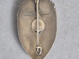 an image of a silver broochle with a key on it