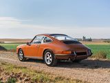 an orange car parked on a dirt road next to a field