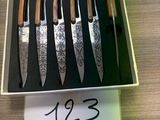 six knives in a box on a table with a price tag