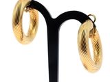 une paire de boucles d'oreilles créoles dorées posées sur un présentoir noir
