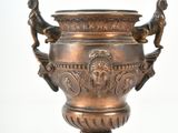 a bronze vase that is sitting on a white surface