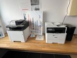 two printers sitting on a wooden desk next to each other