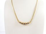 a gold necklace with blue stones on a mannequin neck