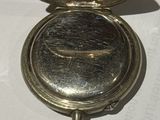 a small silver pocket watch sitting on a white table