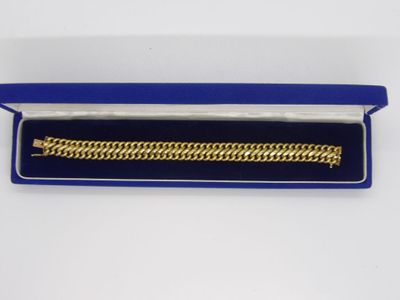 un bracelet en or dans un coffret bleu posé sur une surface blanche