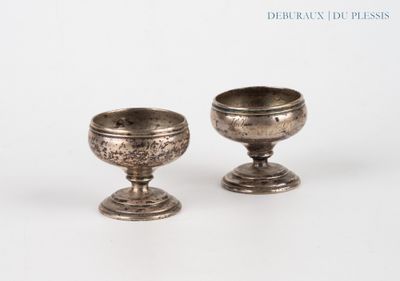 two silver cups sitting next to each other on a white surface