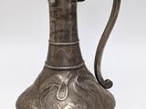 an old silver pitcher with a handle on a white background