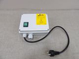 a white box with a green button and a black cord