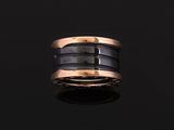 a close up of a black and gold ring on a black surface