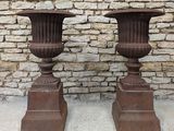 deux grands vases placés l'un à côté de l'autre devant un mur de briques