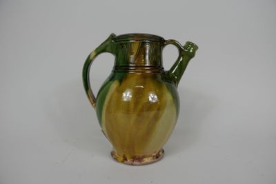 un vase vert et jaune posé sur une surface blanche