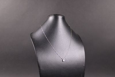 necklace on a mannequin stand with a black background