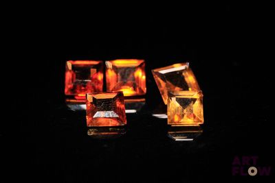 three pieces of yellow and orange glass sitting on top of a black surface