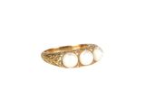 un gros plan d'une bague en or sertie de trois pierres blanches
