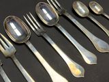 several spoons and forks are lined up on a black surface