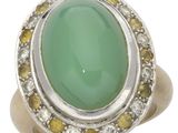 un gros plan d'une bague ornée d'une pierre verte entourée de diamants jaunes et blancs