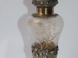 a small glass vase with a gold top on a white surface