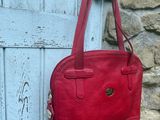 un sac à main en cuir accroché à une porte bleue devant un mur de pierre