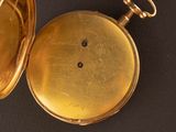a gold pocket watch sitting on a black surface