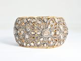 a close up of a gold and diamond bracelet on a white background