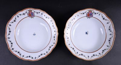 deux assiettes blanches bordées d'or sont posées sur une surface noire