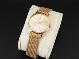 une photo d'une montre-bracelet en or posée sur un tissu blanc