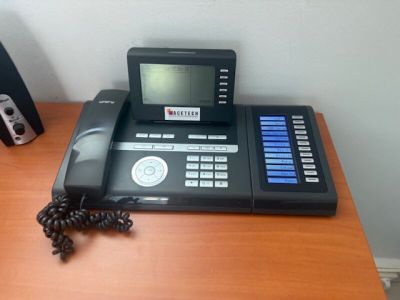 a black telephone sitting on a wooden desk next to a speaker