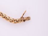 an image of a close up of a gold bracelet on a white surface