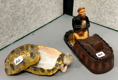 deux figurines représentant un homme assis sur une carapace de tortue