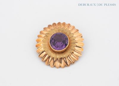 une image représentant une broche en or et en améthyste ornée d'une pierre violette