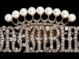 une image représentant une broche ornée de perles et de diamants sur fond noir