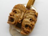 une image représentant deux visages sculptés suspendus à un collier