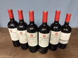 six bottles of red wine are lined up on a wooden table
