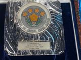 a silver plate in a blue box with a flower design on it