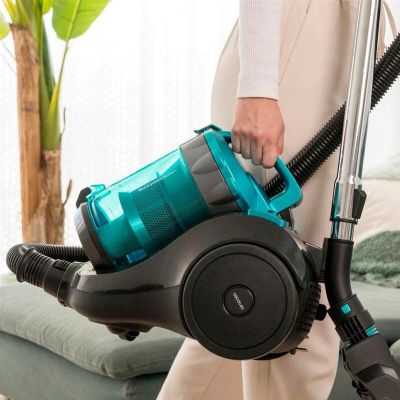 a woman holding a blue and black vacuum in a living room