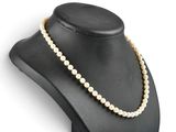a white pearl necklace on a black mannequin