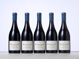 four bottles of red wine are lined up on a table