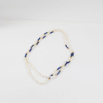 un collier de perles blanches et bleues posé sur un fond blanc