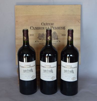 trois bouteilles de vin rouge sont posées devant une caisse en bois