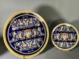 trois assiettes bleues et jaunes ornées de motifs dorés, posées sur un fond gris
