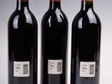 three bottles of red wine are lined up on a table