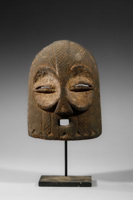 un masque en bois représentant un visage, posé sur un socle