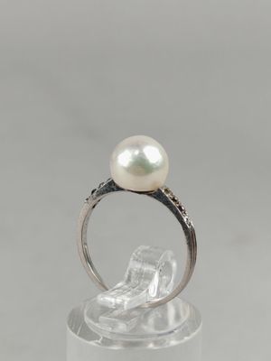 a close up of a ring with a pearl and diamonds on it